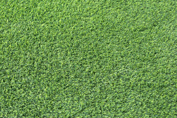 close-up of a lush, green artificial turf. The synthetic blades of grass are perfectly aligned and create a uniform