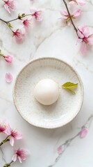 Aerial view of minimal white ceramic plate with cherry blossom and dessert on bright background
