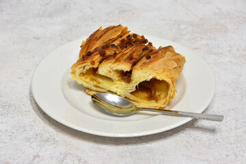 a piece of strudel with syrup and nuts on the white saucer 
