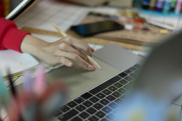 A woman in a red sweater is sitting at a desk with a laptop and a notebook. She is smiling and she...