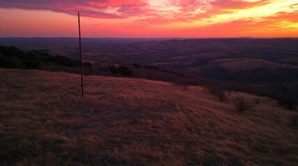 Obraz premium Sunset Over Rolling Hills With Tall Pole