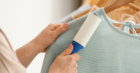 Woman cleaning clothes with lint roller, closeup