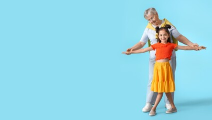 Little girl with her grandma dancing on blue background with space for text