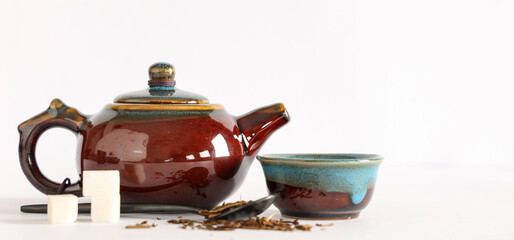 Teapot with cup, spoon of dry tea and sugar on white background