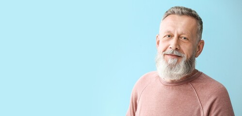 Portrait of handsome senior man on light blue background with space for text
