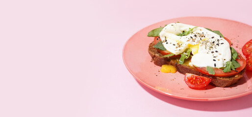 Plate of tasty sandwich with egg on pink background