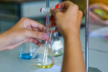 Close-up of a student performing an acid-base titration experiment. Concept of chemistry lab,...