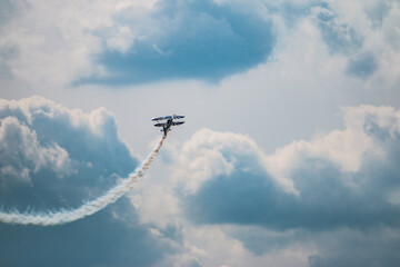 Doppeldecker mit Kondensstreifen, der bei einer Flugshow durch die Wolken fliegt
