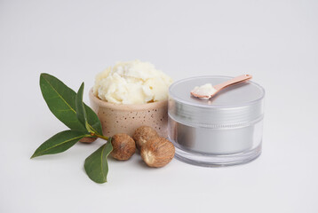 Jar of cosmetic product, shea butter and nuts on light background