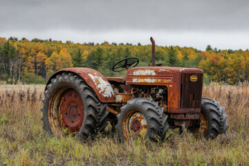 Obraz premium Rusted tractor abandoned in overgrown field