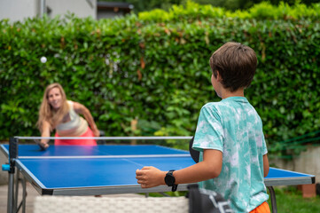 Teenage boy and his mother playing table tennis outside