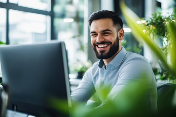 Fototapeta premium Happy Business Owner Smiling While Looking at Screen in Bright Daylight with Minimalist Desk Background Filled with Green Plants and Natural Light