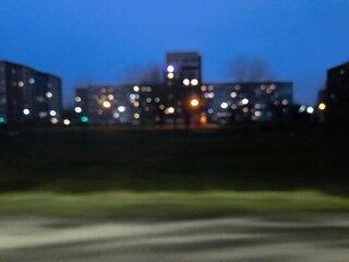 The evening view of apartment buildings in high-rise buildings from the road is blurred.