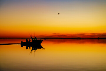 Orange & Red Sunrise with a Silhouetted Boat Cruising with Fisherman on the Great South Bay in Calm Waters on Long Island NY