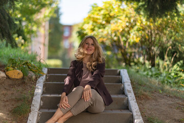 Portrait of a beautiful blonde young girl in a summer city park.