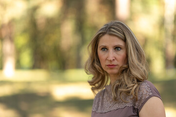 Portrait of a beautiful blonde young girl in a summer city park.