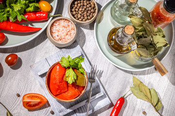 Pickled red peppers with herbs and spices on white table