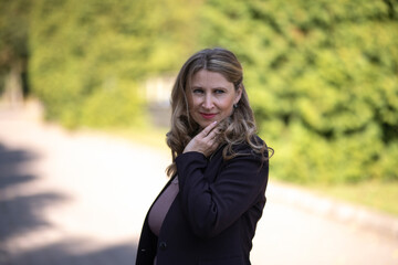 Portrait of a beautiful blonde young girl in a summer city park.