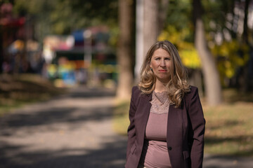Portrait of a beautiful blonde young girl in a summer city park.