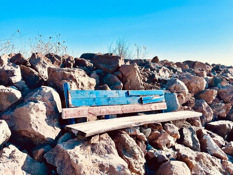 an aold wooden bench and rocks on the beach 