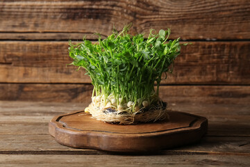 Cutting board with peas micro green on wooden background