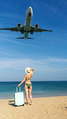 Woman on the beach with a suitcase meets an airplane © I