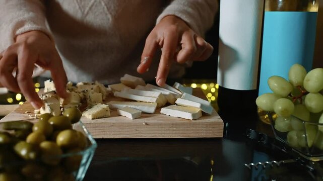 Preparing a cheese board with brie, blue cheese, olives, grapes, and wine. Perfect for a romantic dinner or a gathering of friends. Enjoy the delicious flavors of this Italian feast.