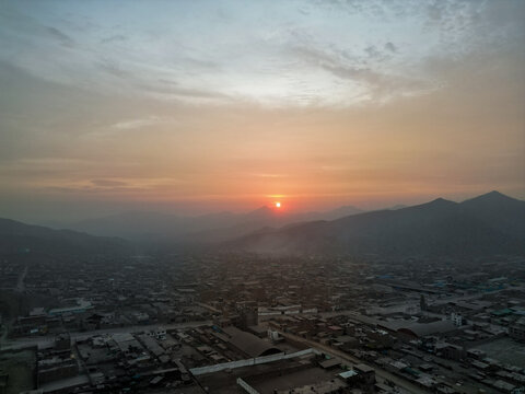 Foggy sunset over the city at the foot of the mountains