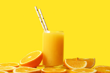 Glass of fresh orange juice and cut fruit on yellow background
