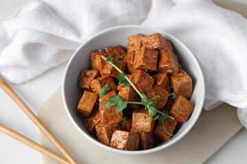 Bowl with pieces of fried tofu cheese and micro green on white background, closeup