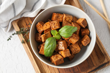 Bowl with pieces of fried tofu cheese and basil on white background, closeup