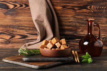 Fototapeta premium Bowl with pieces of fried tofu cheese, rosemary and basil on wooden background