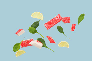 Cut tasty crab sticks with spinach leaves and slices of lemon flying on grey background © Pixel-Shot