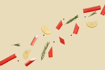 Cut tasty crab sticks with rosemary, peppercorns and slices of lemon flying on green background © Pixel-Shot
