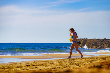 Woman in bikini with camera walk on beach