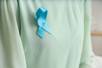 Young woman with turquoise ribbon at home, closeup. Cervical Health Awareness Month