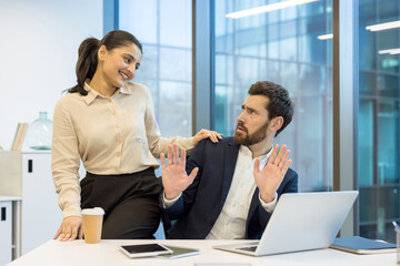 Flirting at work, woman flirting with man at workplace, colleagues working together inside office.