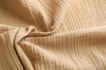 Texture of crumpled linen fabric under natural light in peach fuzz color