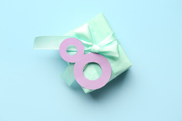 Paper figure 8 with gift box on blue background. Happy Women's Day