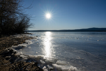 Winter sunny day at a frozen lake with ice floes