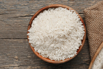 Bowl with raw rice on wooden background