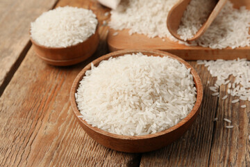 Bowls with raw rice on wooden background