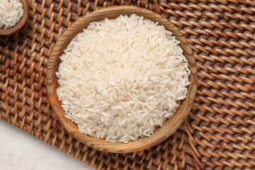 Wooden bowl with raw rice on white background