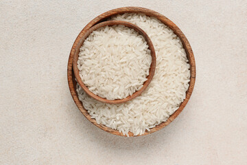 Wooden bowls with raw rice on white background