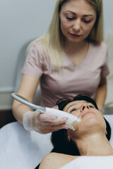 Professional cosmetologist performing LPG facial skin massage for rejuvenation in beauty salon.