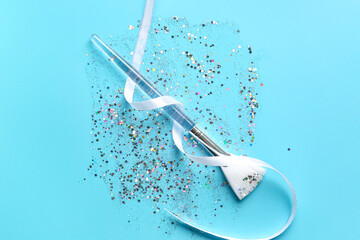 Silver glitter stroke, ribbon and makeup brush on blue background