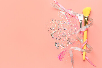 Silver glitter stroke, ribbons and makeup brushes on pink background