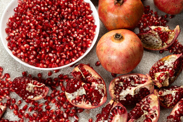 Pomegranate seeds in a plate and lots of whole and peeled pomegranates.