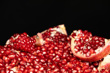 Pomegranate background, lots of peeled pomegranates and seeds, black background