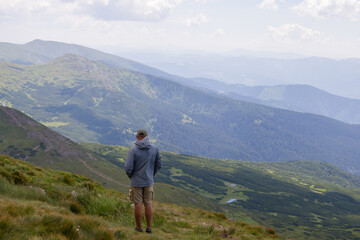 Hiker standing on top of a mountain and looking at the valley